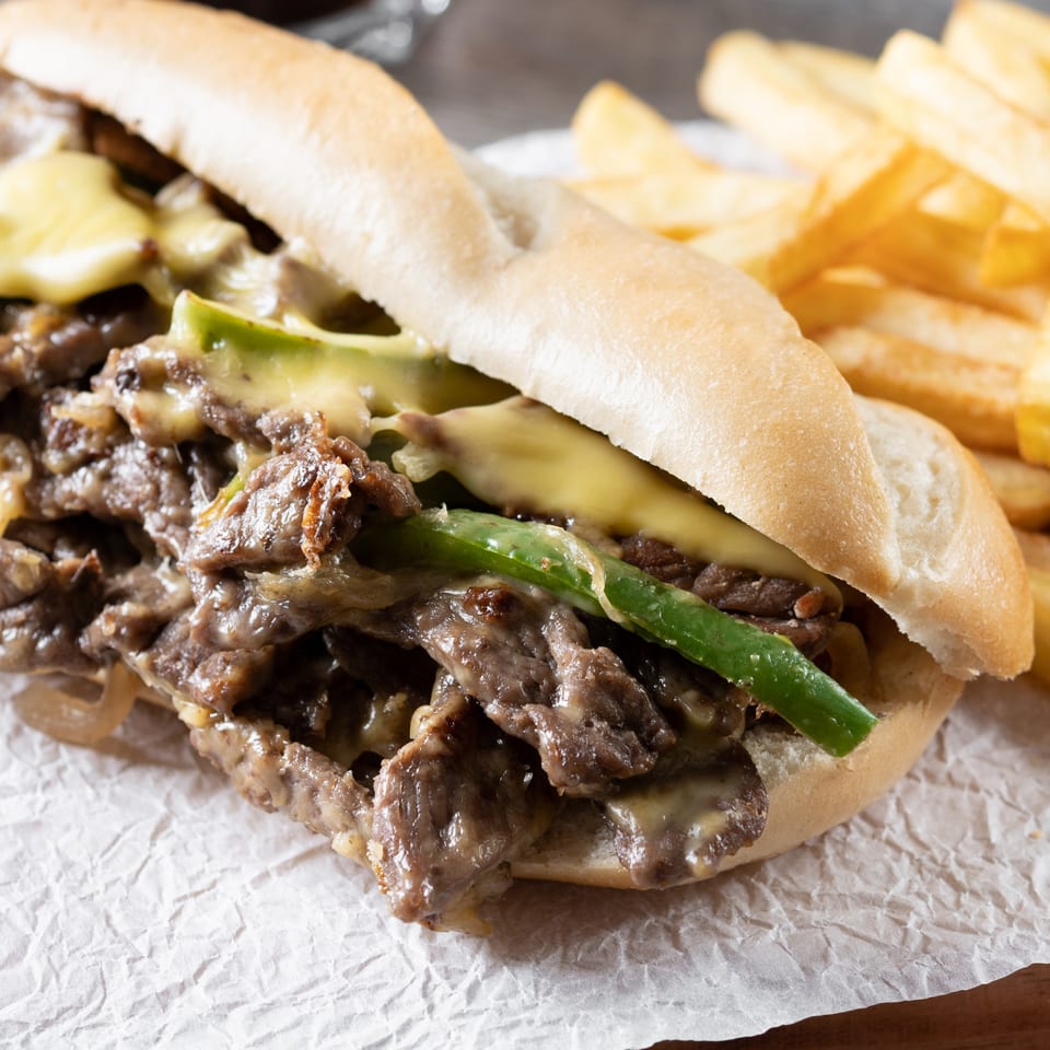 JD's Grill House Philly cheesesteak with melted cheese, green peppers, and a side of fries.